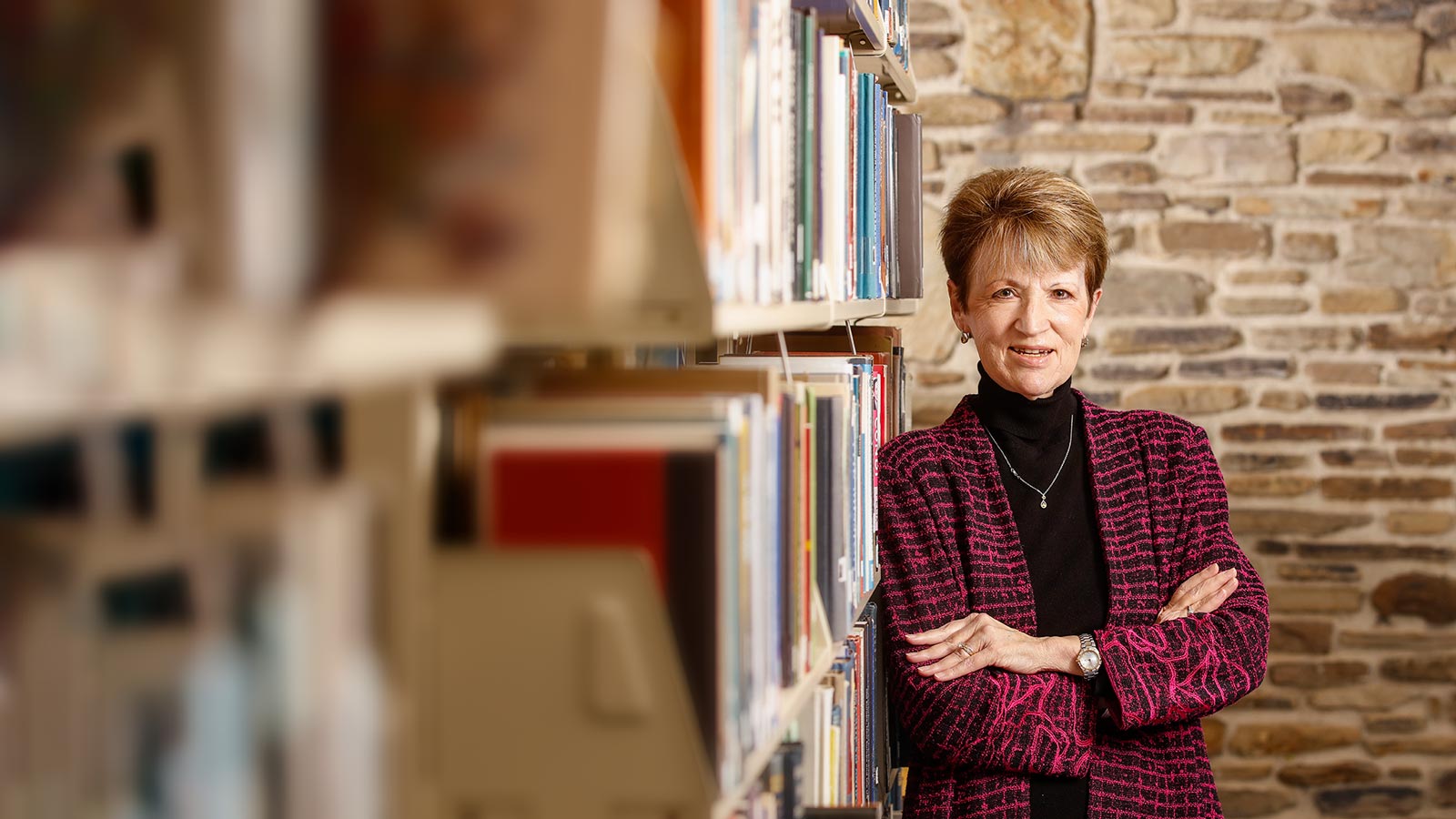 President Shirley Mullen standing in Willard J. Houghton library