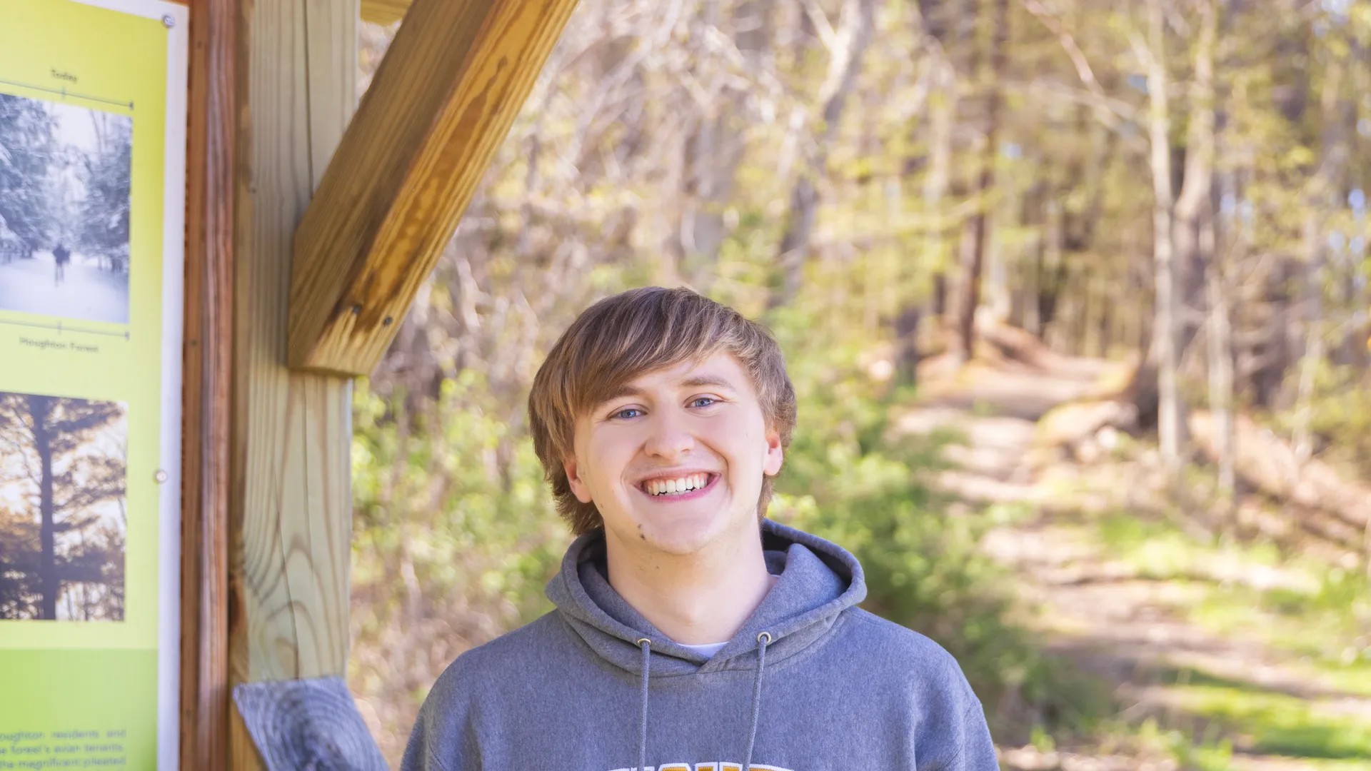 Student smiling outdoors by the houghton trails